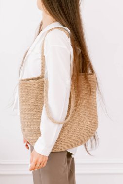 Uzun saçlı bir kadın şık bir çanta taşıyor, evde şık bir moda sergiliyor.