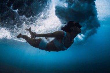 Okyanus dalgaları altında sörf tahtası olmayan kadın ördek dalışı.