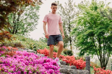 Bahar çiçekli parkın merdivenlerinde yürüyen yakışıklı zayıf adam..