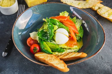 Yumurtalı Sezar salatası, somon, avokado, kiraz domatesleri ve ızgara tost, yakın görüş..