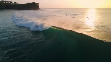 Sörfçülerin drone görüntüsü ve gün batımında sörf dalgaları. Bali 'de ideal sörf dalgaları. Yüksek kalite 4k görüntü