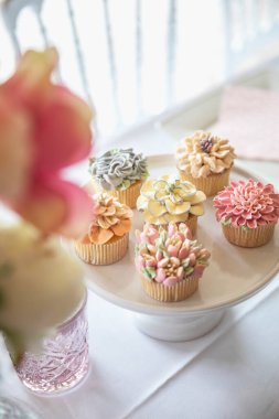 Fresh cupcakes with whipped cream and devorative flower icing served on a plate on party table, wedding,baby shower,high tea, Birthday holiday background