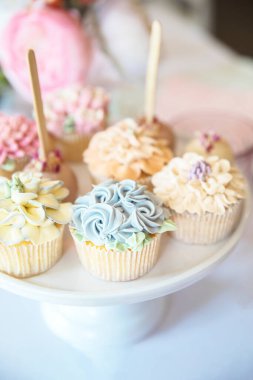 Fresh cupcakes with whipped cream and devorative flower icing served on a plate on party table, wedding,baby shower,high tea, Birthday holiday background