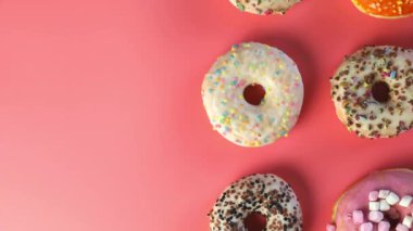 Various freshly colorful delicious sweet donuts in a row. Stop motion. Donuts of different moving, Four glazed sweet donuts. Bakery and food concept. Top view. Chocolate, pink, blue donuts in pack. 4K