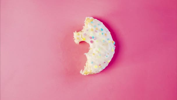 吃美味的甜甜甜圈和粉红色背景的彩色洒水 时间过去了面包店和食品概念 4K多彩的霜冻甜甜圈全景特写 — 图库视频影像