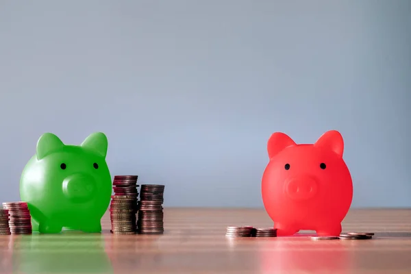 Green piggy bank with many coins and the red with few, broke or big savings. Saving money piggy bank and financial planning concept, difference in wealth copy space
