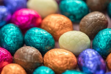 Big pile of colorful wrapped chocolate easter eggs, shiny festive Easter concept, Happy easter close-up candy sweets concept macro various colors