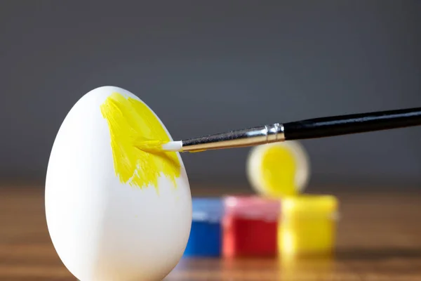 粗糙的刷子正在画一个黄色的易碎的复活节彩蛋 预示着复活节快乐的概念与丰富多彩的业余爱好密切相关 — 图库照片
