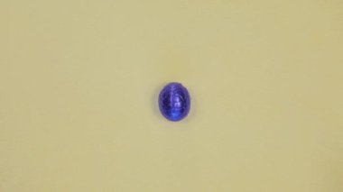Chocolate Easter egg unwrapping sparkling shiny blue foil top view, wrapped easter eggs easting sweets, Happy Easter holiday on yellow background copy space snack