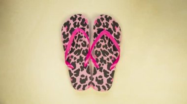 Bright women's flip flops on a colorful yellow background moving from left to right top view, pink panther pattern spring,summer concept