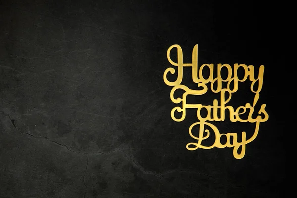 Happy Fathers Day concept. Gold shiny Letters with text Happy Fathers Day on concrete dark black background Flat lay, top view, copy space king crown