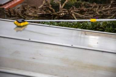 Alüminyumdan yapılmış teras pergola kapağını yıkıyorum. Kirli yosunları fırça sabunu ve suyla temizleyerek bahçeyi teras temizliğinden, işçilerden, konseptten temizler.