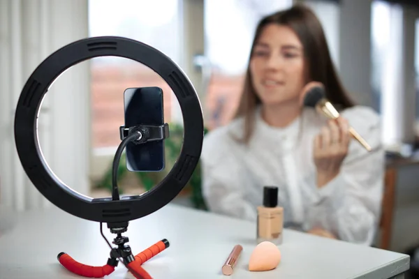 stock image beauty blogging, technology and people concept portrait of a happy smiling girl blogger with ring light and smartphone applying make up at home. making a influencer video Using brush