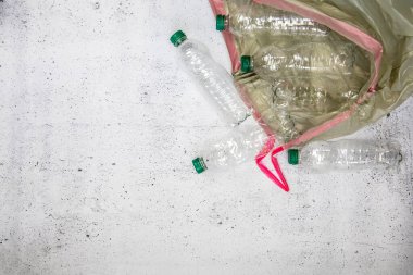 Geri dönüşüm ve ekoloji kavramı. Yukardan toplanan ev atıklarını ayıklamak, düz yerde yatmak. Beyaz beton arka plan boş plastik şişeler kopyalama alanı