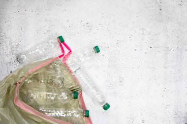 Geri dönüşüm ve ekoloji kavramı. Yukardan toplanan ev atıklarını ayıklamak, düz yerde yatmak. Beyaz beton arka plan boş plastik şişeler kopyalama alanı