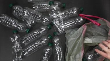 El plastik şişeleri çöp torbasına koyup geri dönüşüme, atık yönetimine ve plastik geri dönüşüme hazır hale getiriyor. Atık plastik şişelerin üst görünümü 4k