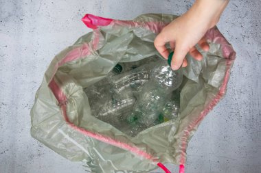 El plastik şişeleri çöp torbasına koyup geri dönüşüme, atık yönetimine ve plastik geri dönüşüme hazır hale getiriyor. Atık plastik şişelerin üst görünümü 4k