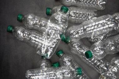 Geri dönüşüm ve ekoloji kavramı. Yukardan toplanan ev atıklarını ayıklamak, düz yerde yatmak. Gri arkaplan boş plastik şişeler kopyalama alanı
