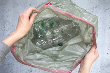 El plastik şişeleri çöp torbasına koyup geri dönüşüme, atık yönetimine ve plastik geri dönüşüme hazır hale getiriyor. Atık plastik şişelerin üst görünümü 4k