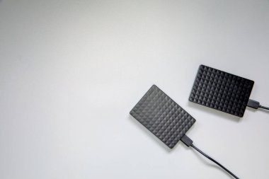 Gri arkaplanda taşınabilir siyah sabit disk HDD izole edildi. Serin düz üst görünüm, kopyalama alanı. Bilgisayarlar için veri depolama kavramı, metin için teknoloji alanı