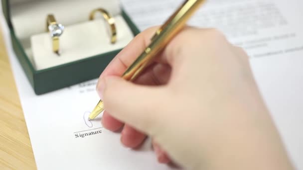 계약서에 펜으로 결혼반지를 서명하는 서약을 클로즈업 매크로 — 비디오