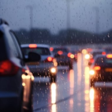 Yağmurlu bir günde otoyolda trafik sıkışıktı. Araba gözlüklerinde yağmur damlaları vardı. Bulanık arkaplan, hareket bulanıklığı, akşam yoğunluğu