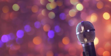 Stüdyo mikrofonu neon ışıklarda. Bokeh arkaplanındaki ses kayıt ekipmanları. Podcast, müzik konsepti mikrofon kopyalama alanı