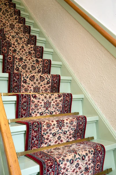 Vintage wooden staircase with antique carpet runner close-up, retro design. steps of a staircase in antique home, interior