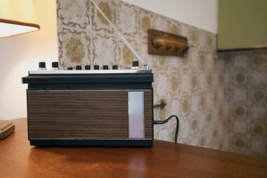 70 'lerin tarzı oturma odasında Retro vintage radyo, FM kanalı müzik çalıyor, eski moda bir radyo çalar ahşap bir masanın üzerinde duruyor. Köyde şık bir mutfak, pencereden gün ışığı. kopyala