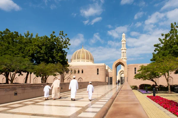 Müslümanların ailesi Umman, Muscat 'taki Sultan Qaboos Büyük Camii' ne giriyor. Duvarlarda Kuran yazılıdır..