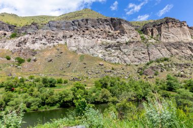 Gürcistan 'daki Vardzia mağara manastırı, Erusheti Dağı manzarası oyulmuş mağaralar, tüneller ve kayalar ve Kura Nehri' ndeki evler, yaz manzarası.