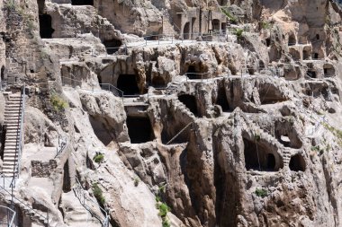 Caves and tunnels linked with stairs and ladders in Vardzia Cave monastery complex in Georgia, mountain slope with carved underground city.