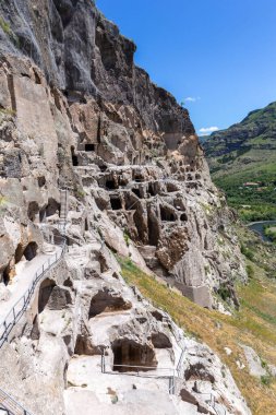 Vardzia cave monastery complex in Georgia, mountain slope with caves, tunnels and dwellings carved in the rock, Kura river valley in the background.