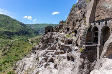 Vardzia cave monastery complex in Georgia, mountain slope with caves, tunnels and dwellings carved in the rock, Kura river valley in the background.