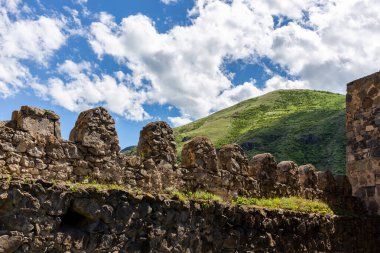 Khertvisi Fortress stone defence crenellated wall with battlements and green Lesser Caucasus mountains in the background, Meskheti region, Georgia.