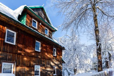 Wooden mountain shelter on Hala Slowianka in Beskid Zywiecki mountains, Poland, in winter, with trees covered with snow.