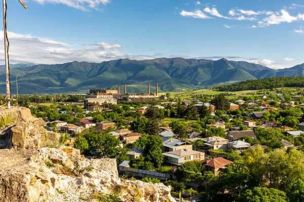 Landscape of Surami, small town (daba) in Georgia with ruins of old Soviet era soda factory and rural architecture, seen from Surami fortress with defense wall in the foreground.