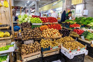 Kutaisi, Georgia, 04.06.21. Market stall with local vegetables and lady selling products in Kutaisi Central Market (Green Bazaar,  Mtsvane Bazari) hall.