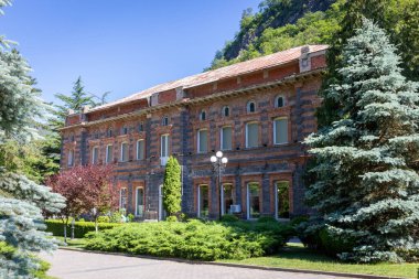Borzhomi Şişe Fabrikası Borjomi Central Park 'ta, eski kırmızı tuğlalı bina yemyeşil bitki ve ağaçlarla çevrili..