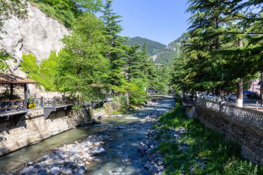 Gürcistan Borjomi Cental Parkı 'ndaki Kura nehri, yaya geçidi, köprüler ve yemyeşil ağaçlarla dolu..