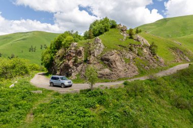 4x4 araç M-20 dolambaçlı çakıl yolunda Tskhratskaro Geçidi 'ne doğru gidiyor, Gürcistan' da Trialeti (Kafkasya) dağları ve yeşil otlaklarla çevrili..