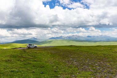 4x4 araç M-20 dolambaçlı çakıl yolunda Tskhratskaro Geçidi 'ne doğru gidiyor, Gürcistan, Javakheti Platosu' nda antik volkanlar ve arka planda dağlar var..