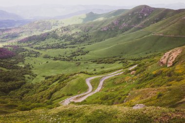 Gürcistan 'ın Tskhratskaro Geçidi' ne giden tehlikeli virajlı M-20 toprak yol, uzakta araba ve Trialeti (Kafkasya) yeşil dağ manzarası,.