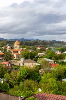 Gürcistan 'ın Akhaltsikhe (Rabati) köyünün kırsal manzarası basit yerleşim binaları ve bir tepenin üzerindeki katolik kilisesi, arka planda daha az Kafkasya dağları.