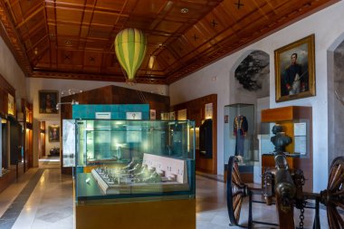 Segovia, İspanya, 03.10.21. Segovia Alcazar Müzesi 'ndeki müze, silah ve askeri gösterilerle dolu odanın içi, vitrinler, top, sıcak hava balonu ve portreler..