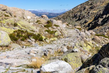 Sierra de Gredos dağlarındaki Plataforma de Gredos 'tan Laguna Grande Gredos Gölü' ne giden taş yürüyüş yolu, kuru kahverengi çimenler, sonbahar, İspanya.