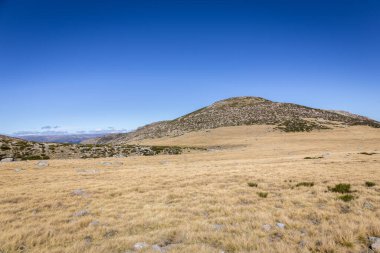 Sonbaharda Sierra de Gredos dağ manzarası, kurak, çorak bitki örtüsü ve kayalık tepeler, İspanya 'nın Laguna Grande Gredos adasına giden patikadan görülüyor..