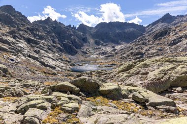 Sierra de Gredos 'taki Laguna Grande de Gredos, arka planda yüksek kayalık dağlar, sonbahar manzarası.