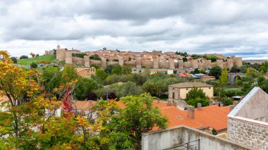 Avila şehrinin yüksek manzarası ünlü ortaçağ şehir duvarları siperleri, Gotik mimarisi ve çevresindeki yeşil bitki örtüsüyle.