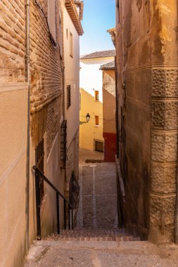 Dar bir ortaçağ kaldırımlı caddesindeki taş merdivenler kiremitli çatıları, bakımsız ön cepheleri ve klasik sokak lambaları olan eski konutlar, Toledo, İspanya.